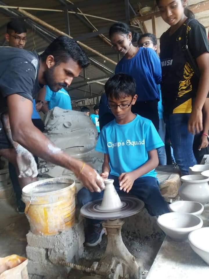 Mahavisnoo (left) teaches kids how to make a clay pot.