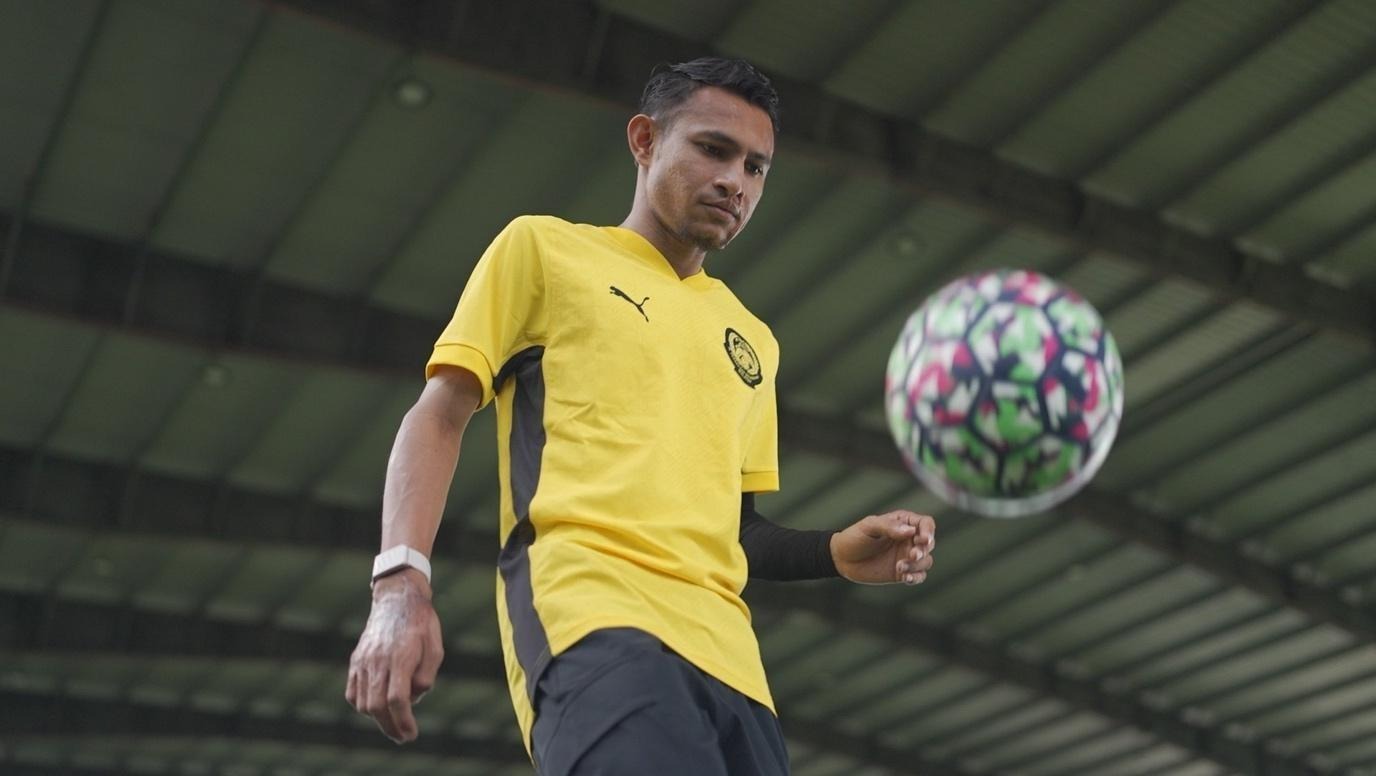 A person in a yellow shirt and black shorts
Description automatically generated